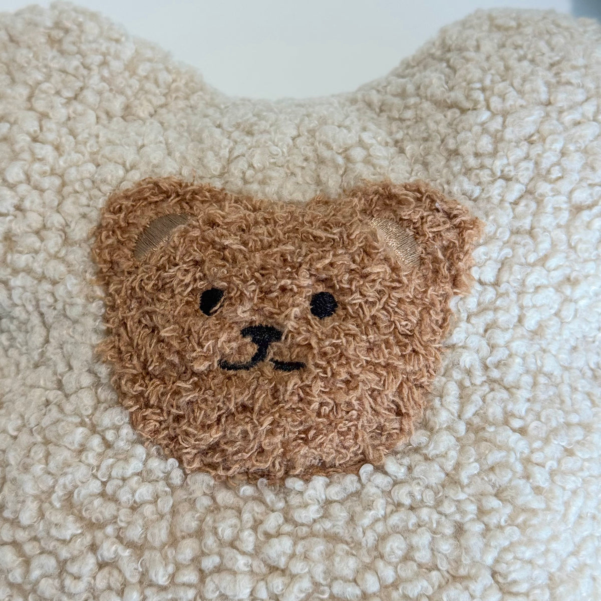 Nahaufnahme des POUFET Knister-Teddys aus Bouclé in Beige – Teddy-Gesicht und weiche, lockig gekräuselte Stoffstruktur