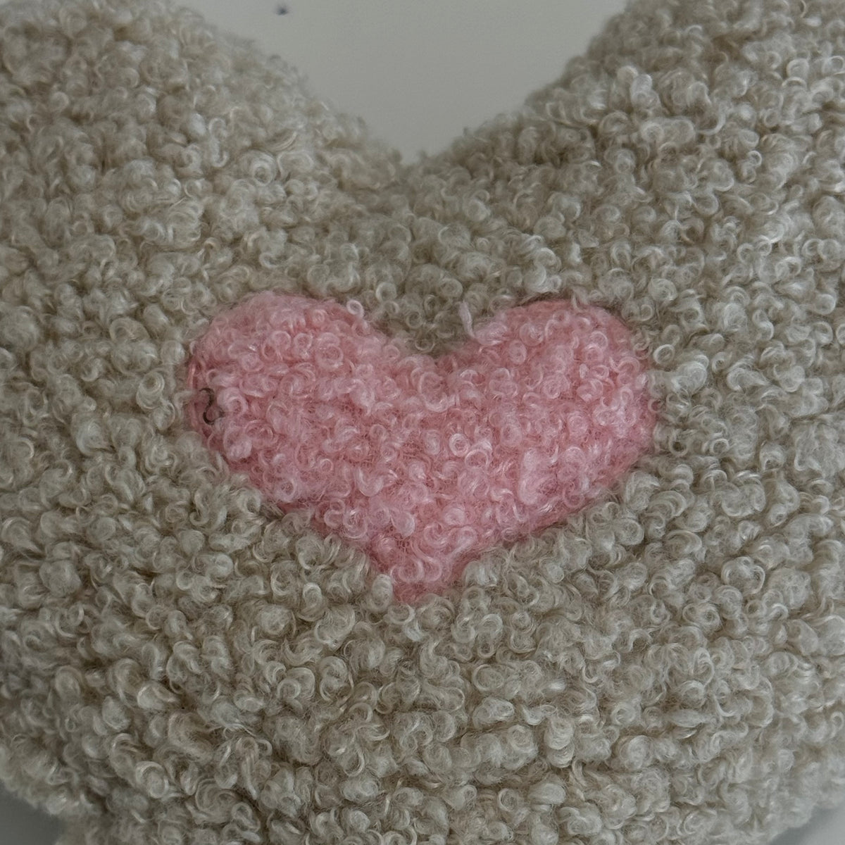 Nahaufnahme des POUFET Knister-Herzens aus Bouclé – rosa Herz und weiche, lockig gekräuselte Stoffstruktur