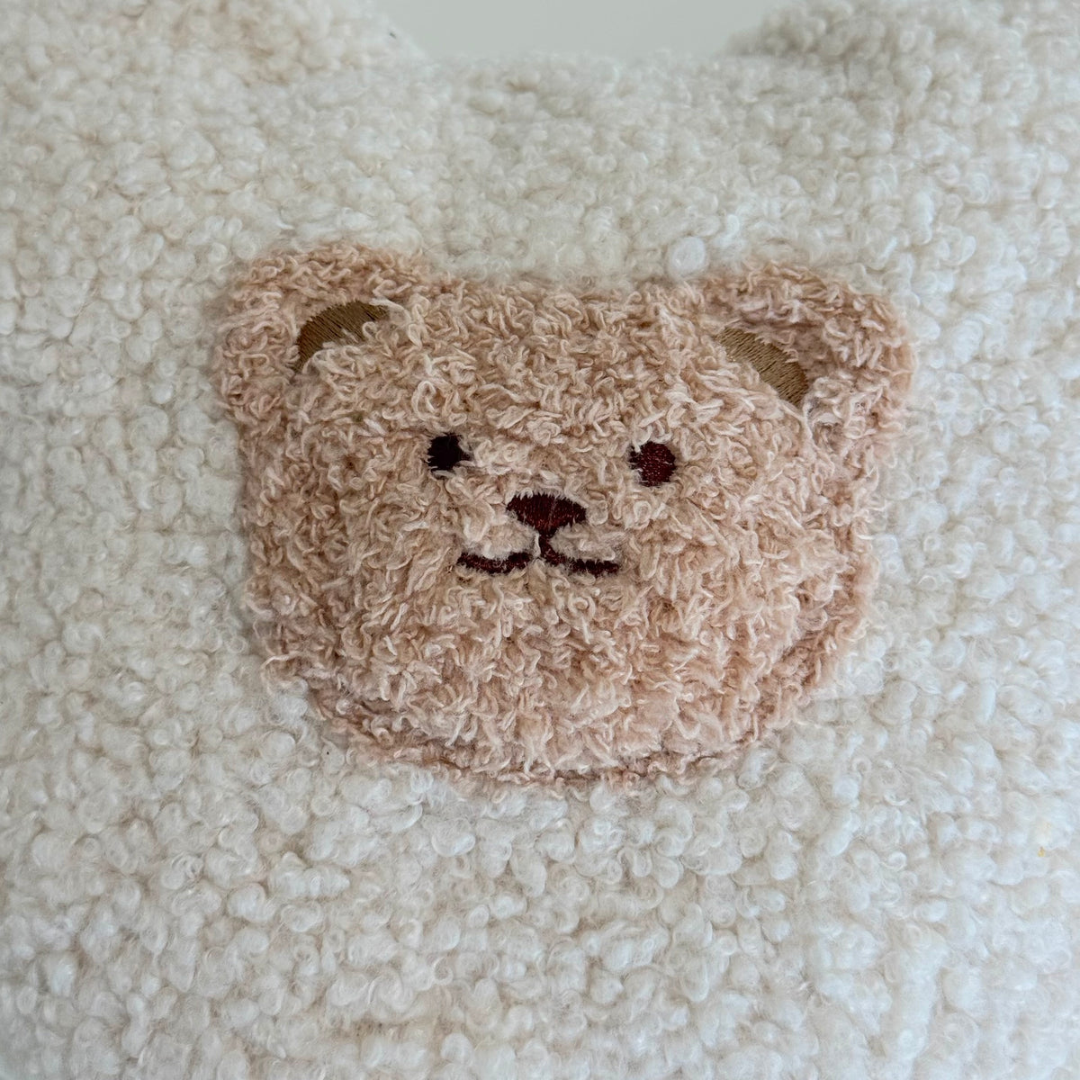 Nahaufnahme des POUFET Knister-Teddys aus Bouclé in Creme – Teddy-Gesicht und weiche, lockig gekräuselte Stoffstruktur